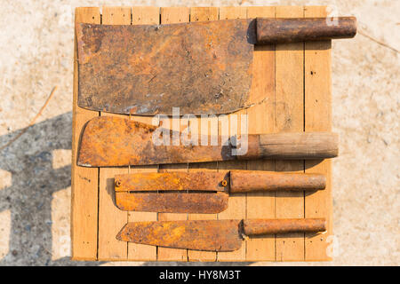 Rostige Messer auf Holz-Fliesen, Bauer Geräte in Thailand, Top View Fleischerbeil mit Fleischermesser Stockfoto