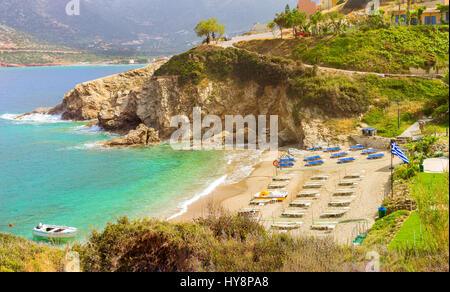 Sandy Evita und Karavostasi Strand im Meer, die Bucht von Bali Resort Dorf. Blick auf Küste, umspült von Wellen und Liegestühle mit Sonnenschirmen Sonnenbaden wo t Stockfoto