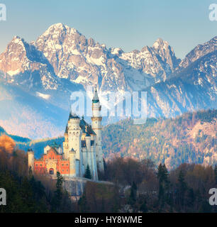 Das berühmte Schloss Neuschwanstein im Hintergrund der schneebedeckten Berge bei Sonnenaufgang in Deutschland. Schöne Frühlingslandschaft mit Burg, Bergspitzen eines Stockfoto