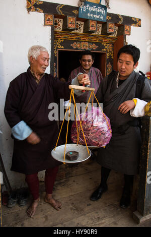 Ein junger Mann kaufen Paprika von einem alten Bauern im traditionellen Kleid Bhutan.  Tamchog, Bhutan. Stockfoto