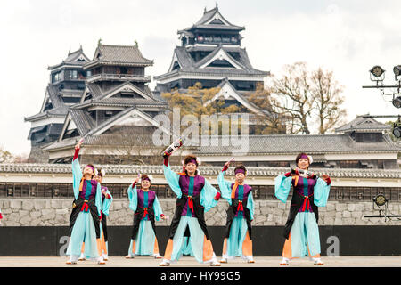 Hinokuni Yosakoi Dance Festival in Japan. Team von Reife Frauen tanzen auf der Bühne in Schwarz und Türkis Kostüm mit Kumamoto Schloss im Hintergrund. Stockfoto