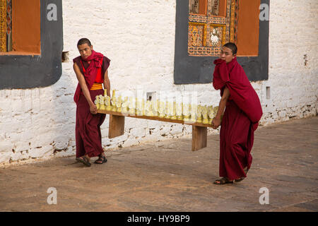 Zwei junge buddhistische Mönche tragen Torma oder Yak-butter Skulpturen für eine buddhistisch-Zeremonie in Punakha Dzong, Punakha, Bhutan. Stockfoto