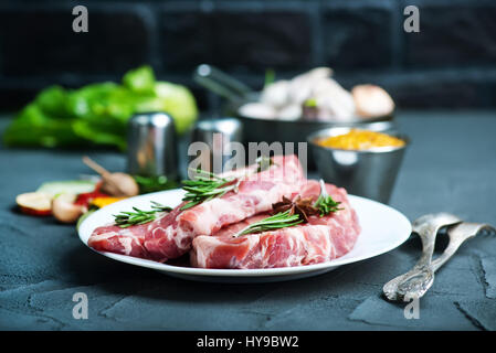 rohes Fleisch mit Gewürz auf Teller und auf einem Tisch Stockfoto