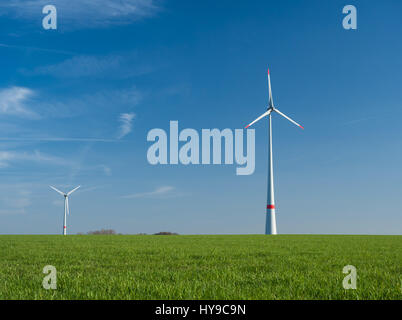 zwei Windkraftanlagen auf einer grünen Wiese und sonniges Wetter Stockfoto