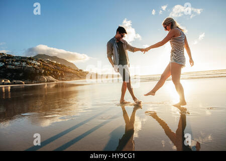 Schöne junge Paar Hand in Hand und spielen am Ufer. Glückliche junge romantische Paar in Liebe Spaß am Strand. Stockfoto