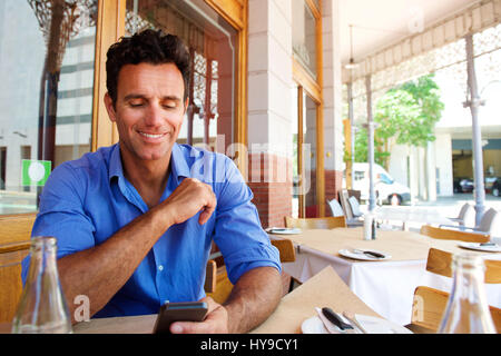 Porträt eines Geschäftsmannes mit Handy am Straßencafé sitzen Stockfoto