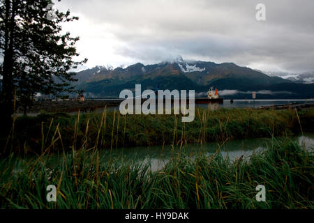 Eine Landschaft mit Bergen und Rasen in Seward, Alaska mit einem Boot mit Kohle in der Ferne geladen wird. Stockfoto