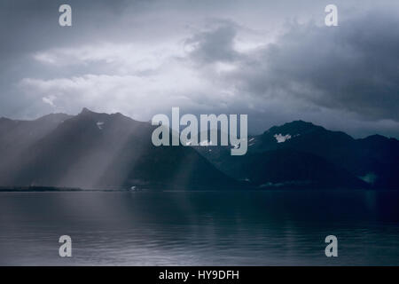 Strahlen der leichte Gipfel durch die Wolken am frühen Morgen über die Berge und das Meer in der Nähe von Seward, Alaska. Stockfoto