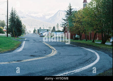 Eine Kurve in der Strasse mit Bergen im Hintergrund in der Stadt von Seward, Alaska. Stockfoto