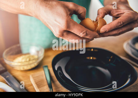 Frau, Kochen und Eiern in die Platte in der Küche zu Hause zu brechen Stockfoto