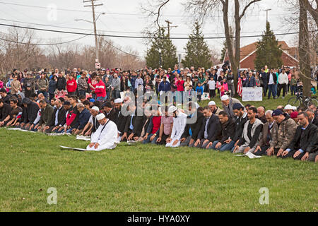 Detroit und Dearborn, Michigan, USA. 2. April 2017. "Nachbarn Brücken bauen": mexikanisch und muslimischen Einwanderern März von St. Gabriel-Kirche in der American Muslim Society Moschee, Einigkeit zu zeigen und gegen Präsident Trump plant, eine Grenzmauer zu bauen und um muslimische Reisen in die USA zu stoppen. Auf der anderen Straßenseite von der Moschee statt Muslime Freitagsgebete in einem Park, während nicht-Muslimen beobachtete leise. Bildnachweis: Jim West/Alamy Live-Nachrichten Stockfoto