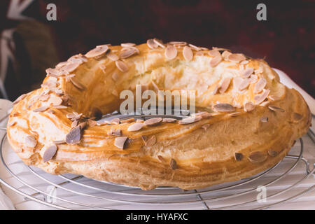 Frisch gebackene große Profiterole Kuchen voller in bedeckt mit gerösteten Mandeln und Schokolade Flocken Abkühlung auf der Folterbank Stockfoto