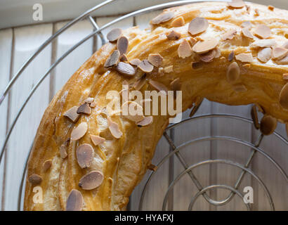 Frisch gebackene große Profiterole Kuchen voller in bedeckt mit gerösteten Mandeln und Schokolade Flocken Abkühlung auf der Folterbank Stockfoto