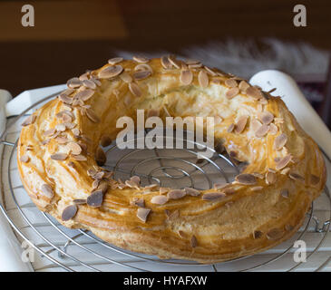 Frisch gebackene große Profiterole Kuchen voller in bedeckt mit gerösteten Mandeln und Schokolade Flocken Abkühlung auf der Folterbank Stockfoto