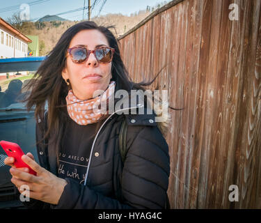 Junge Frau mit Sonnenbrille, von etwas, während eines Anrufs mit einem smart phone abgelenkt. Stockfoto