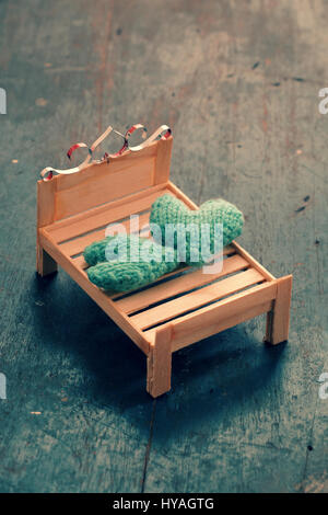 Zwei Herzen werden zusammen, Abbildung paar in der Liebe, achten Sie darauf, liebevoll, grünes Herz auf handgefertigte Mini Möbel als Stuhl, Schaukel, Bett auf Holz Hintergrund Stockfoto