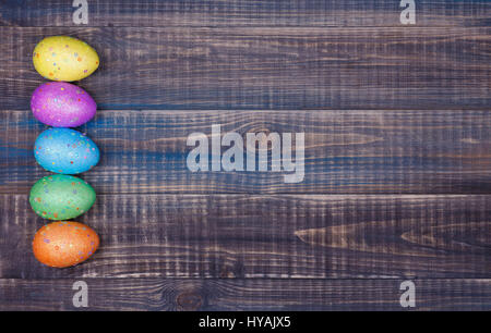Auf einem Holztisch liegen fünf bunte Ostereier. Platz für text Stockfoto