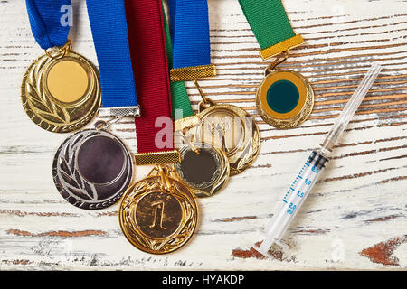 Medaillen und Spritze auf Holz. Stockfoto