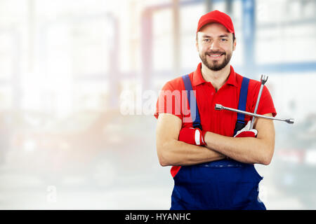 Auto-Reparatur-Service - Kfz-Mechaniker mit Schraubenschlüssel in der hand lächelnd Stockfoto