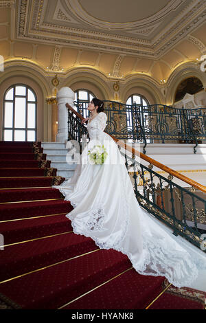 Braut auf Treppen. Hochzeits-Kleid. Grüne Hochzeit Bouquet. Editorial. Stockfoto