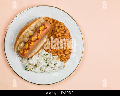 Hot Dog in einem Brötchen mit Baked Beans und Kartoffelsalat blass Orange Hintergrund Stockfoto