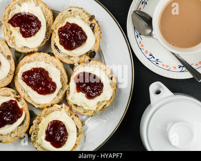 Scones mit Clotted Cream und Strawberry Jam mit Tee vor schwarzem Hintergrund Stockfoto