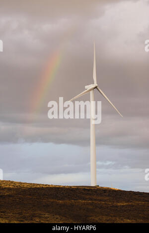 Regen fällt, erstellen einen Regenbogen hinter eine große Windkraftanlage Stockfoto