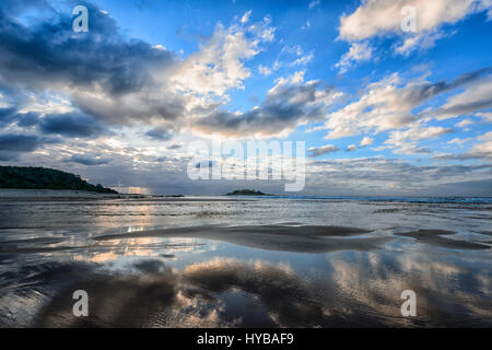 Stimmungsvollen Blick auf Wolken Reflexionen im Meer bei Sonnenaufgang über Conjola Strand, Shoalhaven, South Coast, New-South.Wales, NSW, Australien Stockfoto