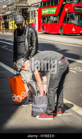 Ein Mann blickt durch seine Abercrombie and Fitch Einkaufstasche auf Regent Street, London, UK Stockfoto