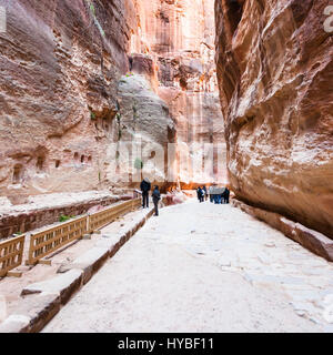 PETRA, Jordanien - 21. Februar 2012: Menschen in der Nähe von Nischen in Al Siq-Schlucht, Petra Altstadt im Winter. Felsen-schneiden Stadt Petra entstand etwa 312 B Stockfoto