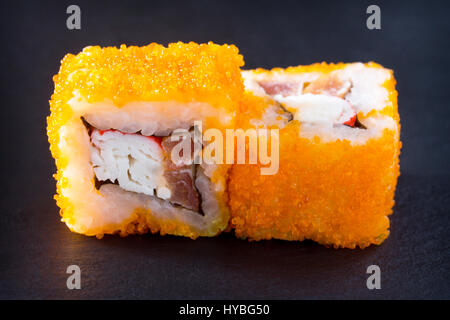 Rolle auf einer Tafel Schiefer - grün Tobiko-Rogen zu isolieren, Barsch Izumidai, pikanter Sauce, Reis, Nori, Gurke. Stockfoto