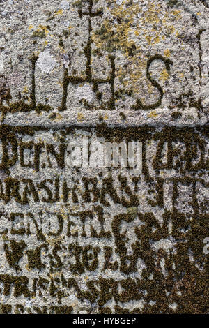 Alten Grabstein mit grünem Moos für Hintergrund bedeckt.  Moos in Form der Buchstaben auf alten Grabstein. Stockfoto