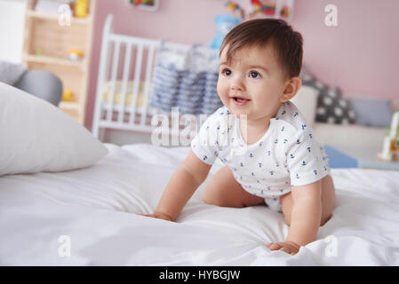 Lächelnden jungen kriechen auf dem Bett Stockfoto