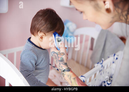 Mutter ist über Söhne Temperatur dafür zu sorgen Stockfoto