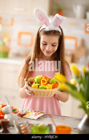 Weibliches Kind betrachten Osternest mit bunten Eiern Stockfoto