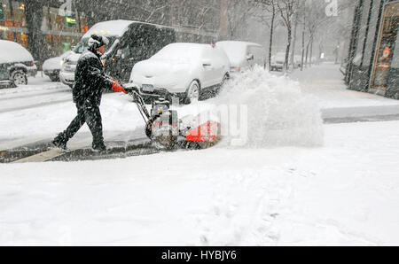 Ein Mann wird mit einer Schneefräse zu löschen Bürgersteig bei starkem Schneefall. Stockfoto