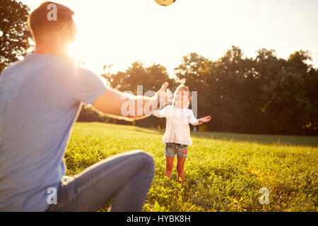 Mädchen mit Vater spielt Ball im Sommer im park Stockfoto