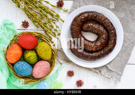 Ostergerichte: buntere gefärbten Eiern, hausgemachter Wurst Ring, willow Zweige auf einem hölzernen Hintergrund. Ansicht von oben. Stockfoto