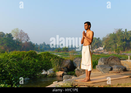 Indischer Mann neben einem Fluss in Süd-Indien Yoga zu praktizieren. Stockfoto