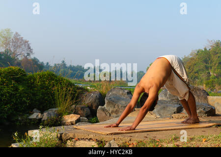 Indischer Mann neben einem Fluss in Süd-Indien Yoga zu praktizieren. Stockfoto