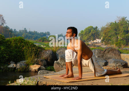 Indischer Mann neben einem Fluss in Süd-Indien Yoga zu praktizieren. Stockfoto