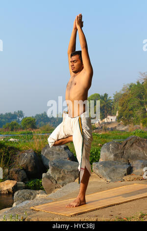 Indischer Mann neben einem Fluss in Süd-Indien Yoga zu praktizieren. Stockfoto