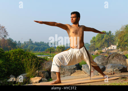 Indischer Mann neben einem Fluss in Süd-Indien Yoga zu praktizieren. Stockfoto