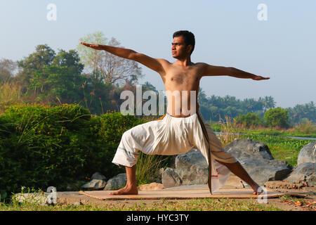 Indischer Mann neben einem Fluss in Süd-Indien Yoga zu praktizieren. Stockfoto