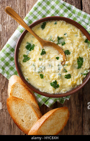 Italienische Küche: Suppe Stracciatella mit Nahaufnahme von Farfalline und Käse in eine Schüssel geben. Vertikale Ansicht von oben Stockfoto