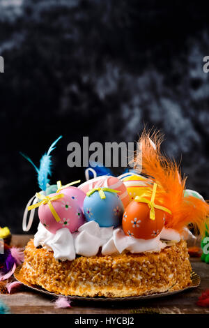 ein Mona de Pascua, einen Kuchen gegessen in Spanien am Ostermontag, garniert mit verschiedenen dekorierten Eiern und Federn in verschiedenen Farben auf einem rustikalen hölzernen su Stockfoto