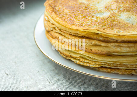 Goldene Crepes auf weißen Teller auf Leinentuch Hintergrund, Closeup, Frühstück, gemütliche Morgen Atmosphäre gestapelt Stockfoto