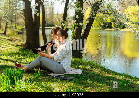 Zwei Frauen sitzen auf Boden mit tablet Stockfoto