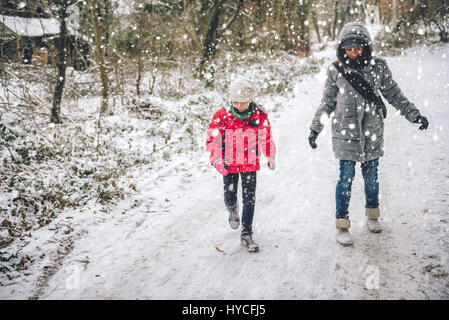 Mutter mit Tochter im weißen Winterwald wandern Stockfoto