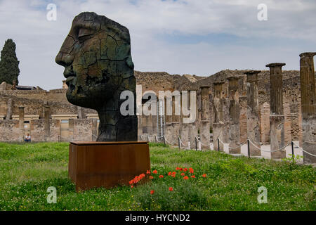 Moderne abstrakte Bronzeskulptur eines römischen Mannes auf die antike römische Stätte von Pompeji in Italien mit dorischen Säulen im Hintergrund Stockfoto